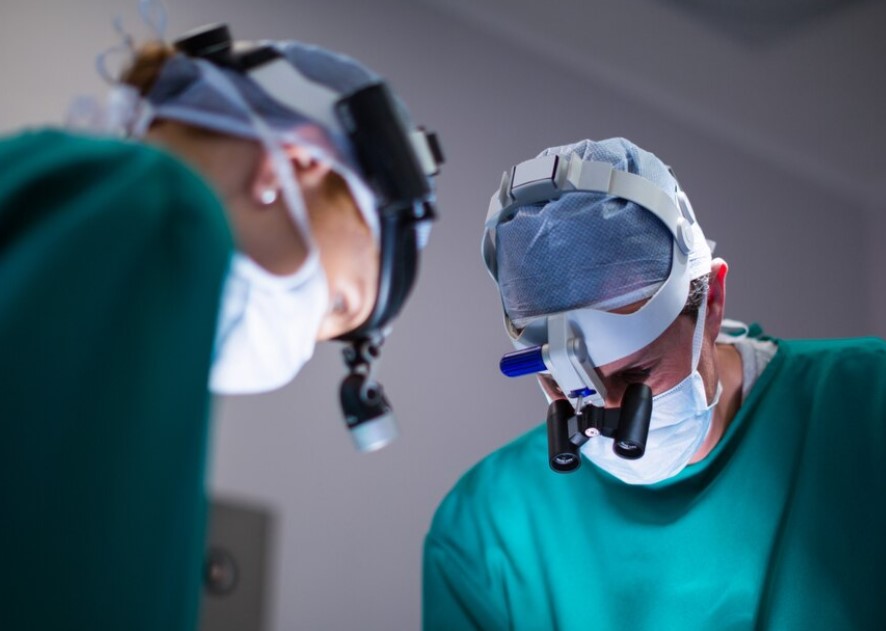 dos dentistas con lentes de precisión y con ropa de quirofano