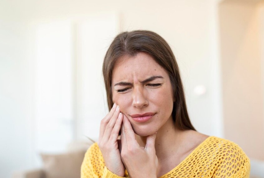 Mujer tocándose la cara con expresión de dolor en las encias