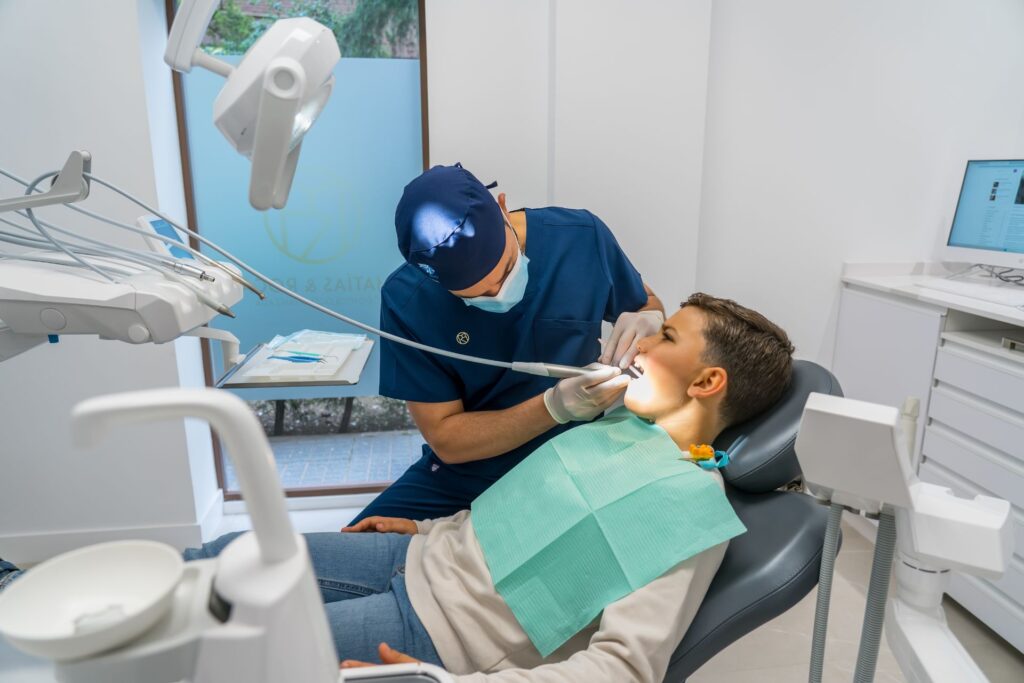 Hombre en silla dental atendiendo a un niño durante una consulta odontológica.